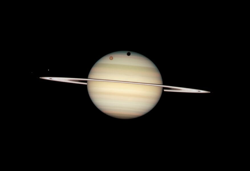 ハッブル宇宙望遠鏡が2009年2月24日に撮影した土星で、4つの衛星が土星の手前を横切っています。
